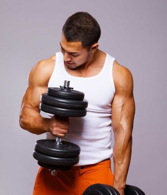 Foto homem musculoso em forma exercitando com halteres