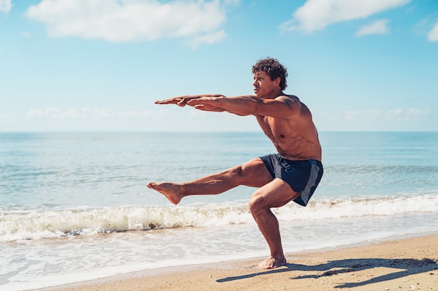 Homem musculoso fazendo exercícios em musculação na praia