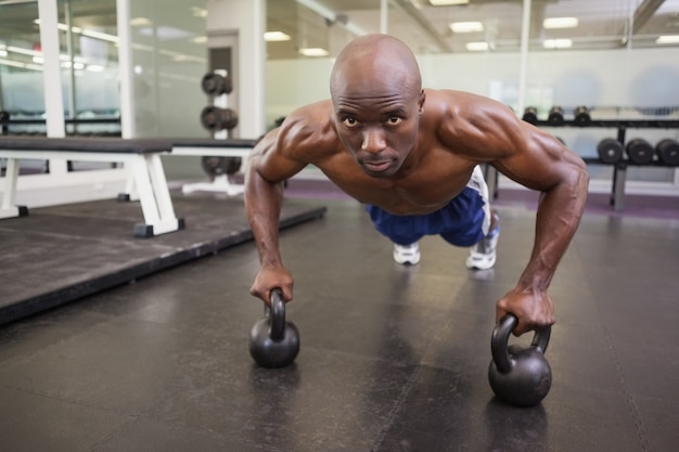 Homem musculoso fazendo flexões na academia