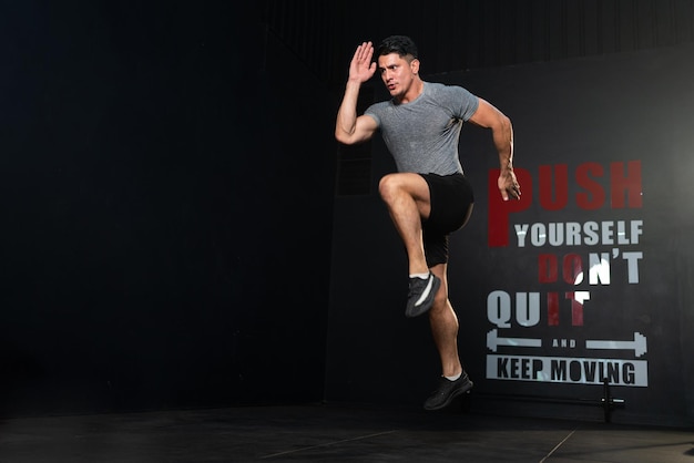 Homem musculoso forte exercitando pulando e posando correndo no clube esportivo de academia de ginástica
