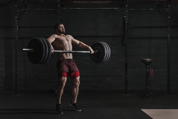 Homem musculoso, levantando uma barra no ginásio crossfit