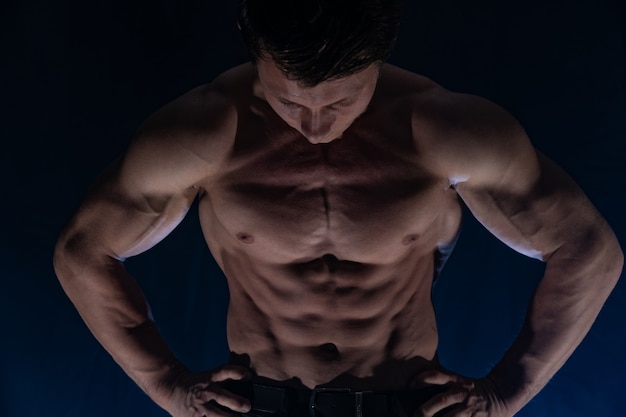 Homem musculoso mostrando músculos isolados no fundo preto estilo de vida saudável