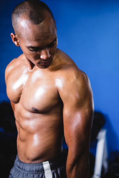 Homem musculoso, olhando para o braço no ginásio