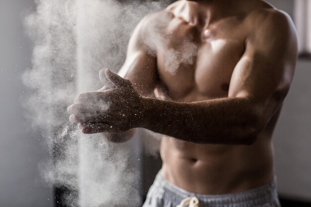 Homem musculoso sacudindo giz das mãos