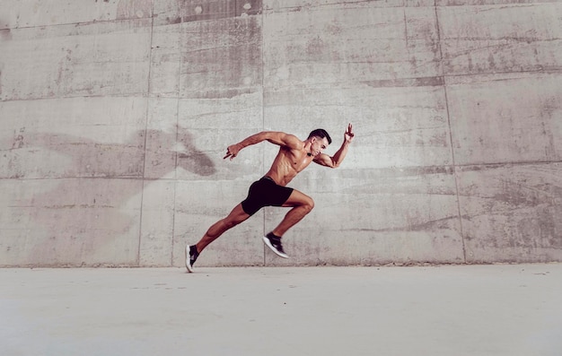 Homem musculoso sem camisa a correr ao ar livre.