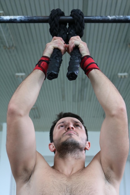 Foto homem musculoso sem camisa a exercitar-se no ginásio.