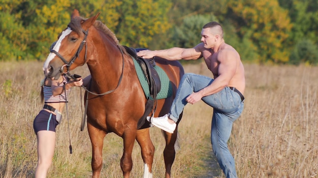 Homem musculoso sem camisa com um cavalo na natureza