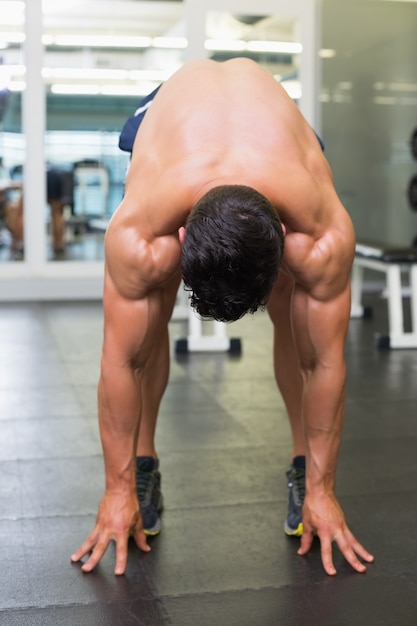 Foto homem musculoso sem camisa dobrado na academia