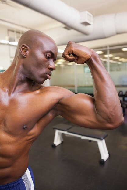 Homem musculoso sem camisa flexionando os músculos