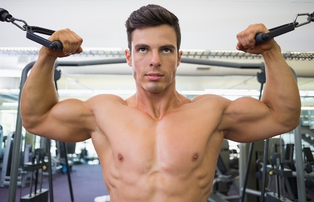 Homem musculoso sem camisa usando banda de resistência na academia