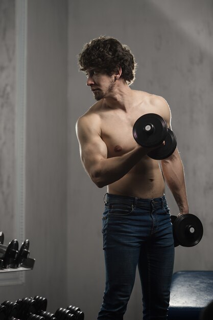 Foto homem musculoso treina halteres bíceps no ginásio, treinamento de mão