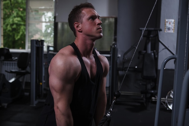 Foto homem musculoso treinando na academia fazendo exercício de tríceps