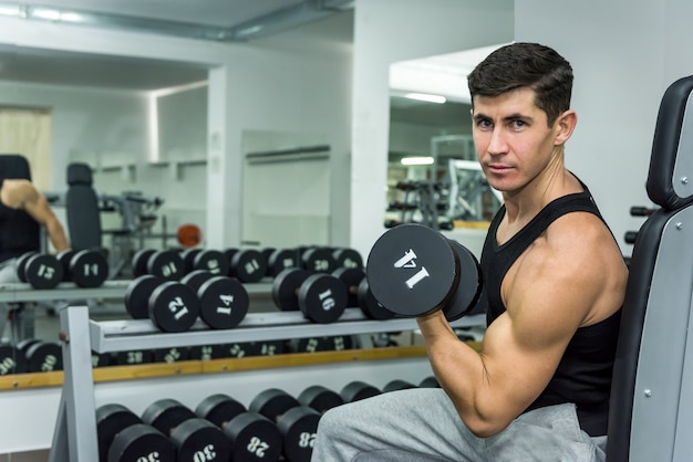 Homem na academia segurando halteres de perto