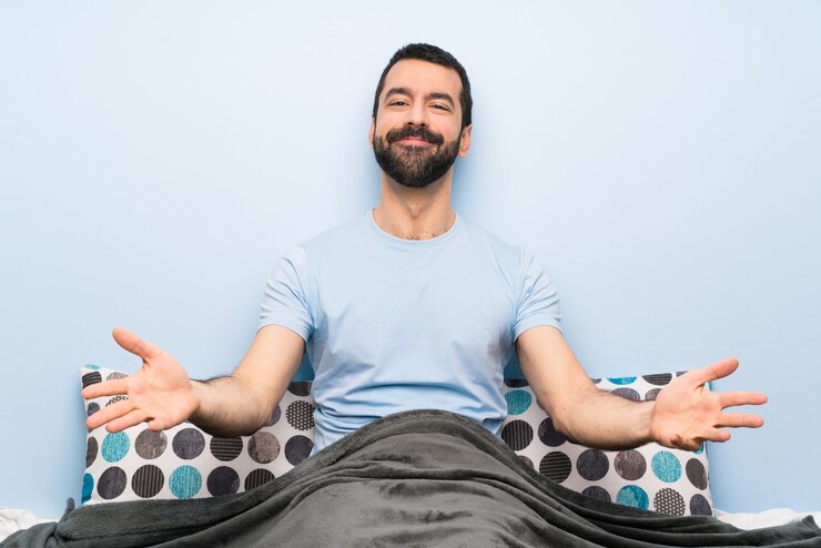 Foto homem na cama, apresentando e convidando para vir com a mão