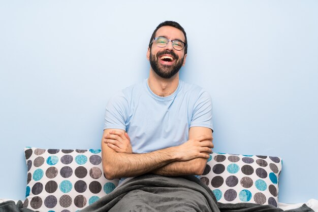 Homem na cama com óculos e sorrindo