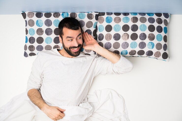 Foto homem na cama em vista superior ouvindo algo colocando a mão na orelha