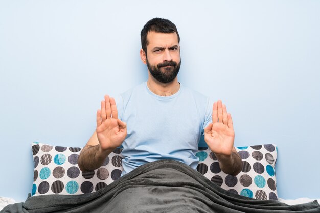 Homem na cama fazendo parar gesto e decepcionado