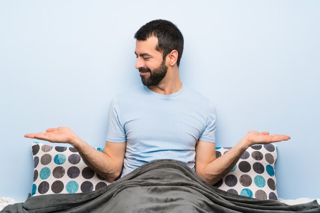 Homem na cama segurando copyspace com as duas mãos