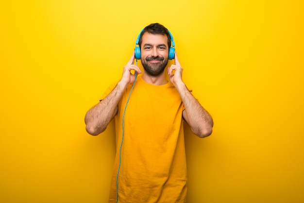 Homem na cor amarela vibrante isolada ouvindo música com fones de ouvido