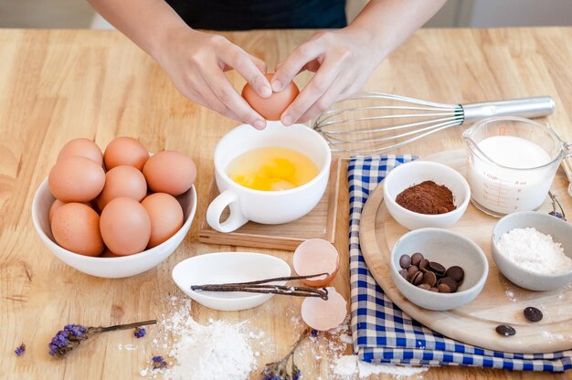 Homem na cozinha cozinhando uma massa Mãos quebra um ovo em uma tigela mãos derramando ovo mordido Conceito de cozimento