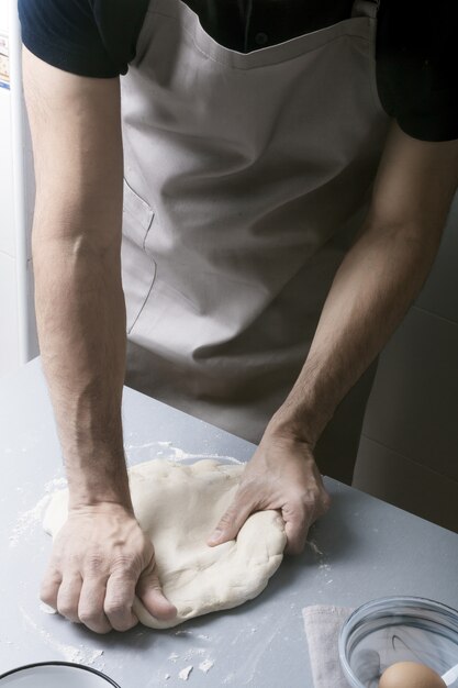 Foto homem na cozinha de casa prepara a massa de pizza com farinha