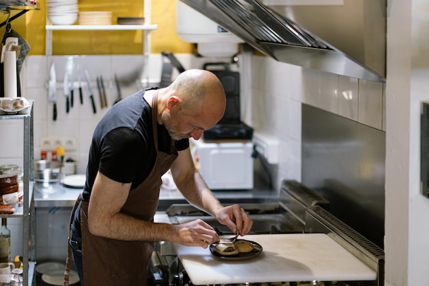 Foto homem na cozinha preparando um mini burguês gourmet