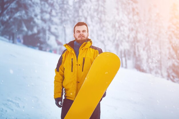 Foto homem na estação de esqui com uma prancha de neve no fundo nevado homem barbudo na paisagem de inverno férias de inverno nas montanhas nevadas com esportes ativos