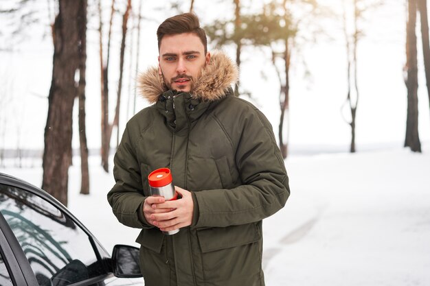 Homem na floresta de inverno perto do carro