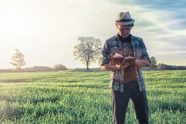 Homem na natureza com mochila e livro de leitura