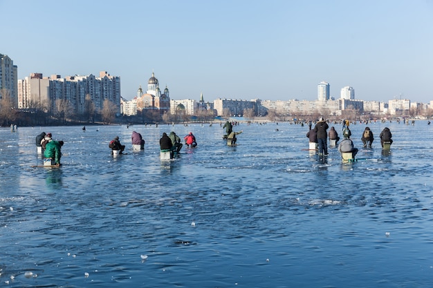 Homem na pesca de inverno, pessoas no gelo do lago congelado, pescadores, paisagem urbana,