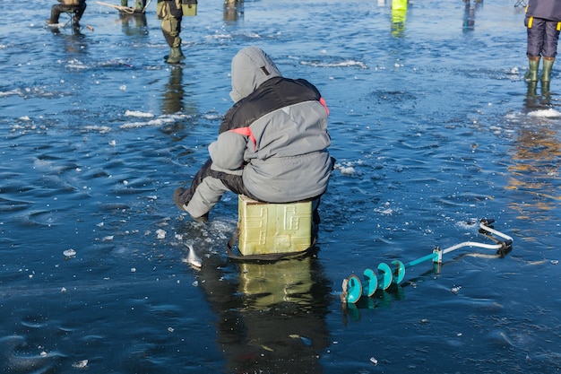 Homem na pesca de inverno, pessoas no gelo do lago congelado, pescadores, paisagem urbana,