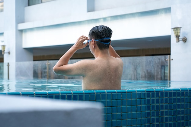 Homem na piscina relaxando e ajustando seus óculos no conceito de férias