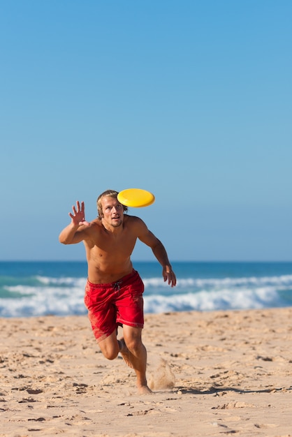 Homem na praia jogando frisbee