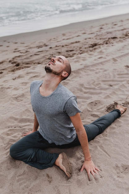 Foto homem na praia praticando ioga