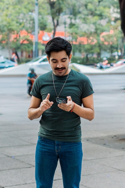 Homem na rua da cidade animado com telefone na mão.