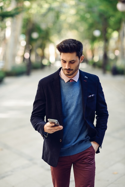 Homem na rua em formalwear com o smartphone na mão.