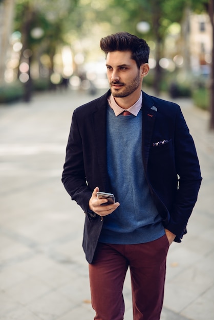Homem na rua em formalwear com o smartphone na mão.