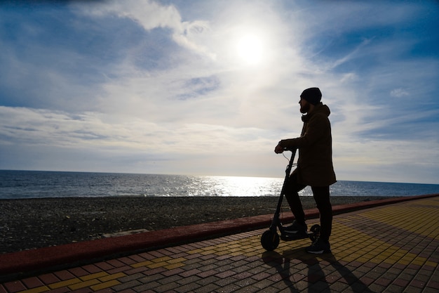 Homem na scooter ao pôr do sol, silhueta, espaço livre