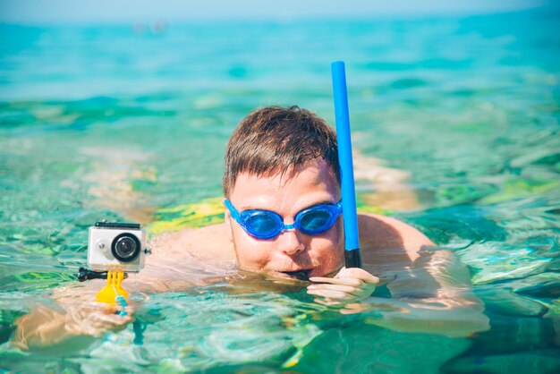 Homem nadando debaixo d'água com máscara e câmera de ação