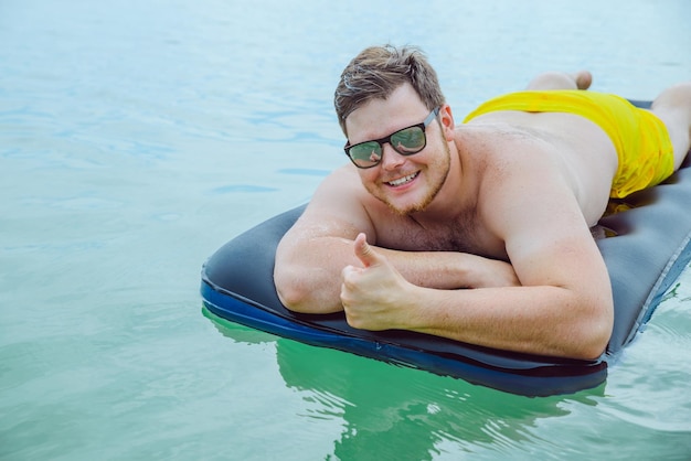 Homem nadando no colchão no mar