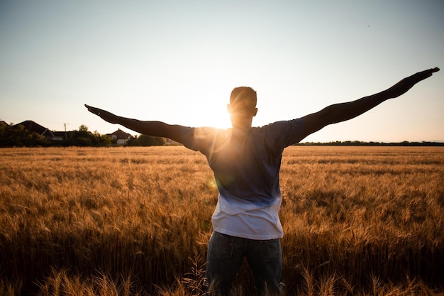 Homem não especificado com as mãos para cima assistindo o pôr do sol