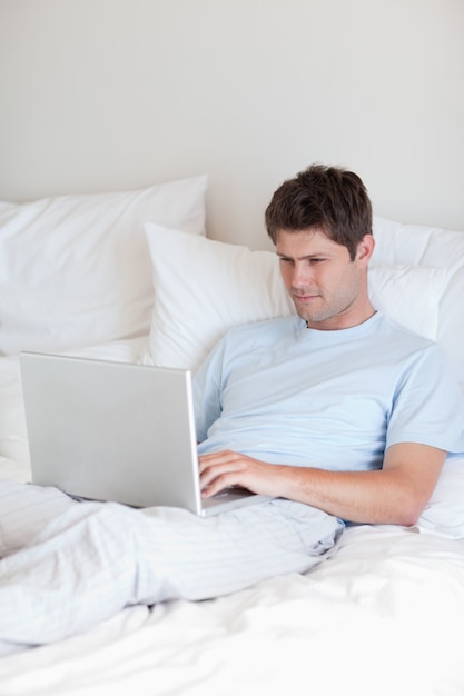 Homem navegando na internet na cama