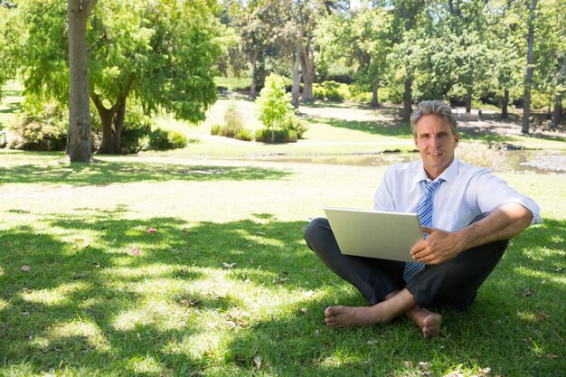 homem negócios com laptop sentado na grama