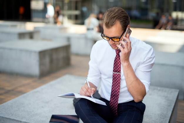 Homem negócios, falando, ligado, a, cellphone, enquanto, escrita, ligado, seu, agenda