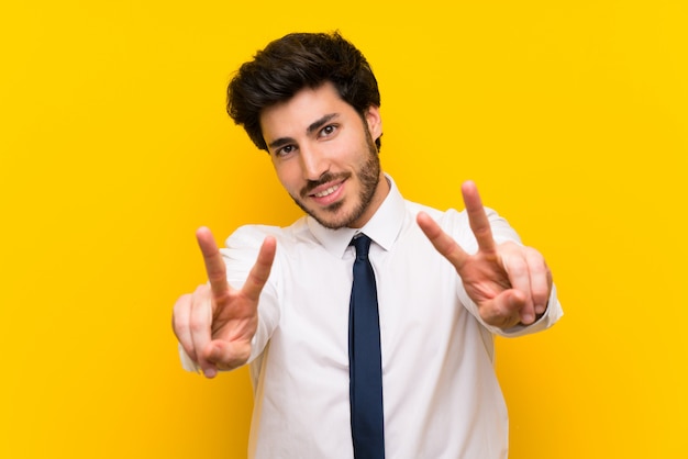 Homem negócios, ligado, isolado, amarela, sorrindo, e, mostrando, sinal vitória