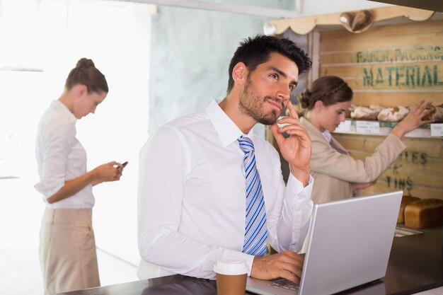 Homem negócios, usando computador portátil, em, cafeteria