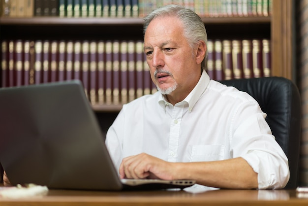 Homem negócios, usando, seu, laptop, em, um, biblioteca