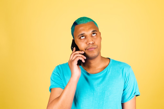 Homem negro africano casual em parede amarela com telefone celular ouvir voz com rosto cansado e entediado