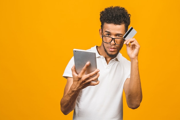 Homem negro afro-americano fazendo compras on-line usando o tablet pc e fazendo o pagamento com cartão de crédito