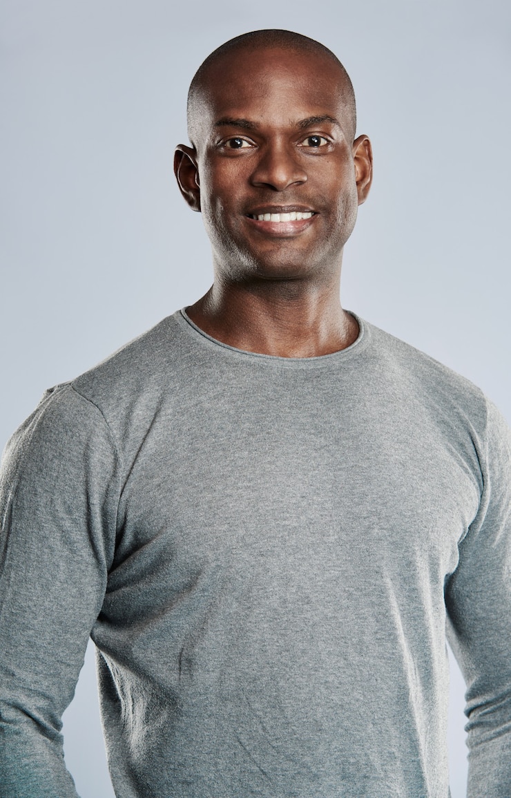 Foto homem negro bonito, solteiro e sorridente com a cabeça raspada em uma camisa cinza com físico musculoso